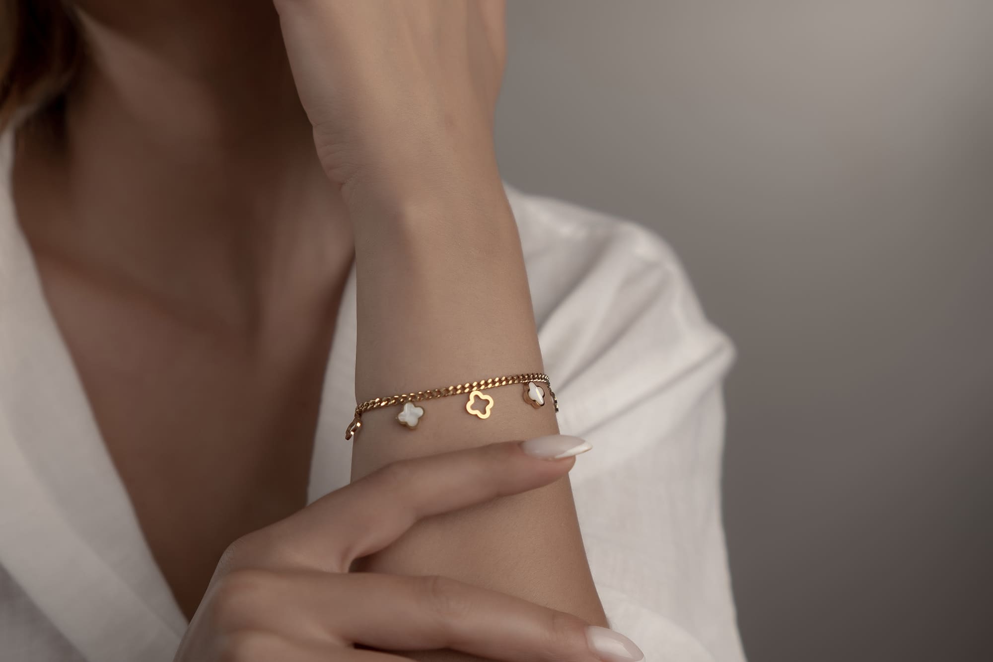 Goldenes Armschmuck mit weissen Perlmutt-Kleeblättern