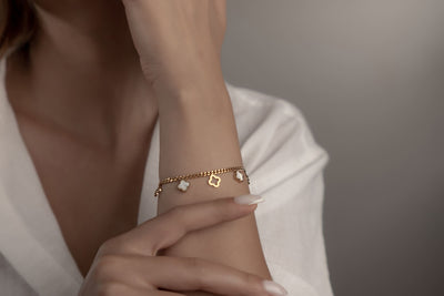 Goldenes Armschmuck mit weissen Perlmutt-Kleeblättern