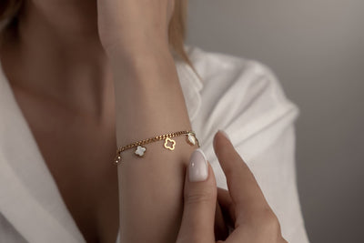 Goldenes Armschmuck mit weissen Perlmutt-Kleeblättern