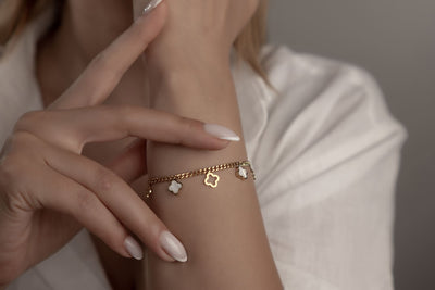 Goldenes Armschmuck mit weissen Perlmutt-Kleeblättern