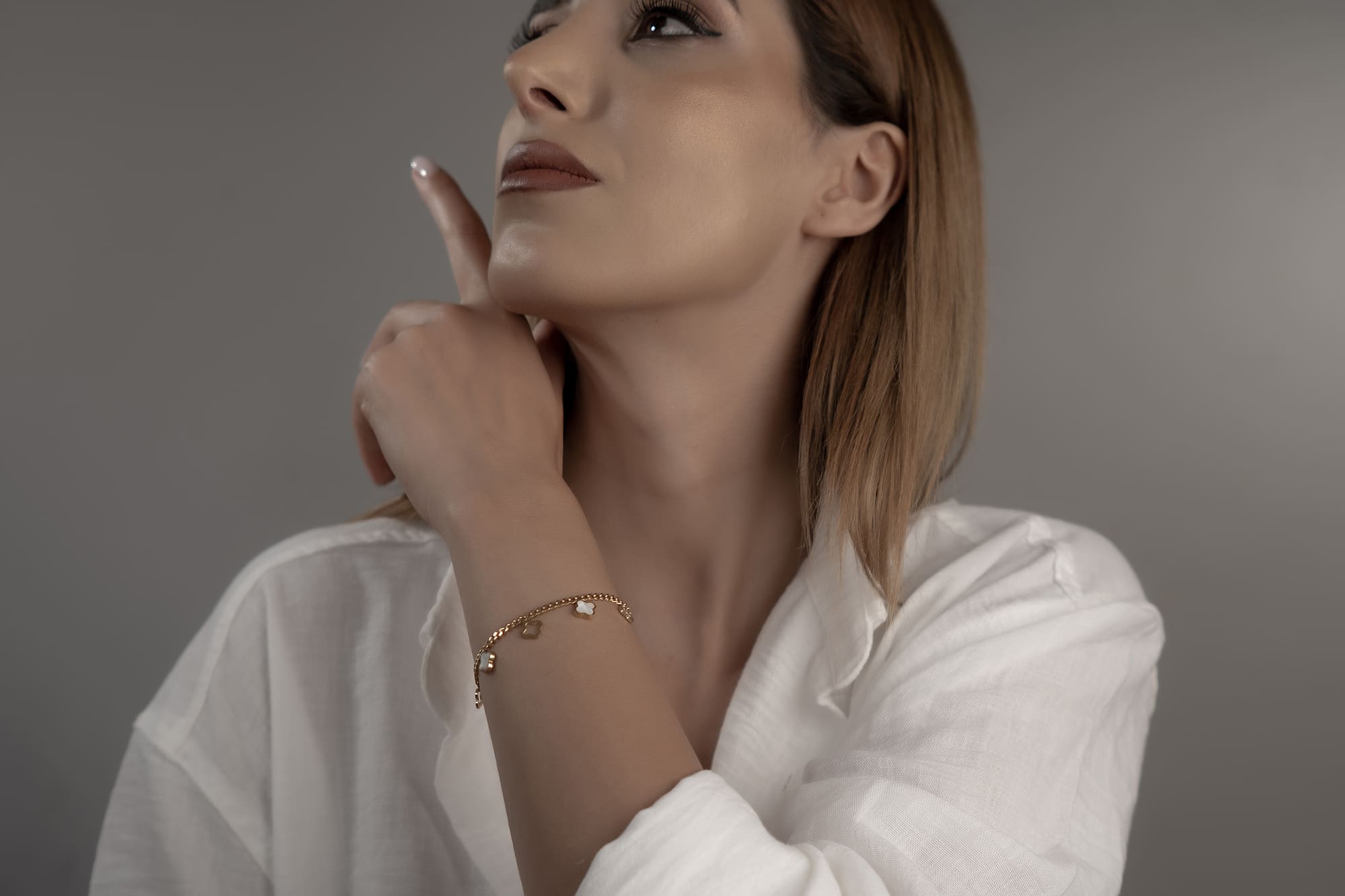 Goldenes Armschmuck mit weissen Perlmutt-Kleeblättern