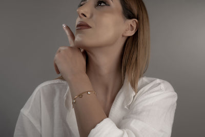 Goldenes Armschmuck mit weissen Perlmutt-Kleeblättern