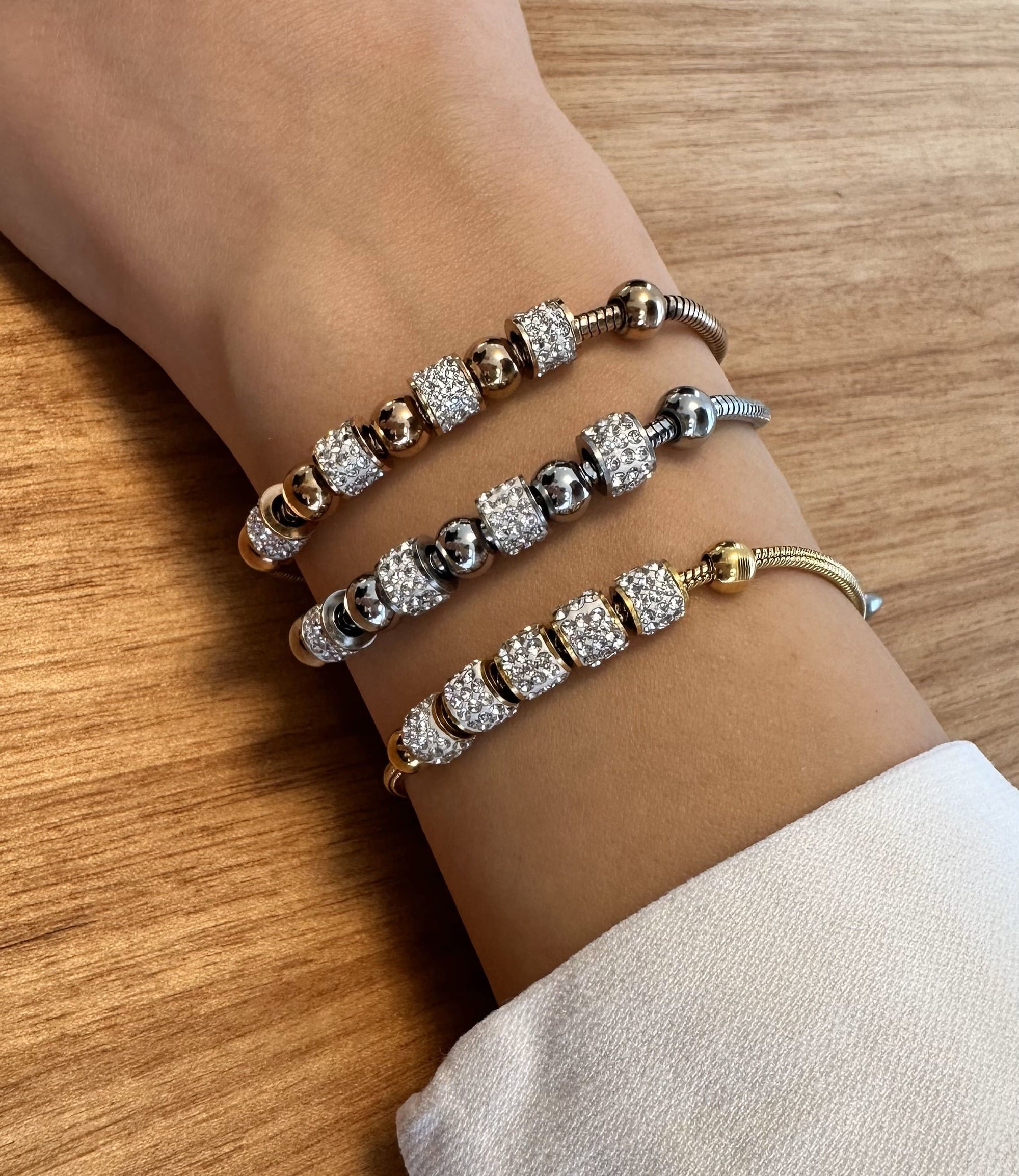 Verstellbarer, goldener Armschmuck mit Zirkonia-Elementen-auf dem Bild ist ein Handgelenk mit diesem Armschmuck sichtbar in Gold, silber und Rosegold