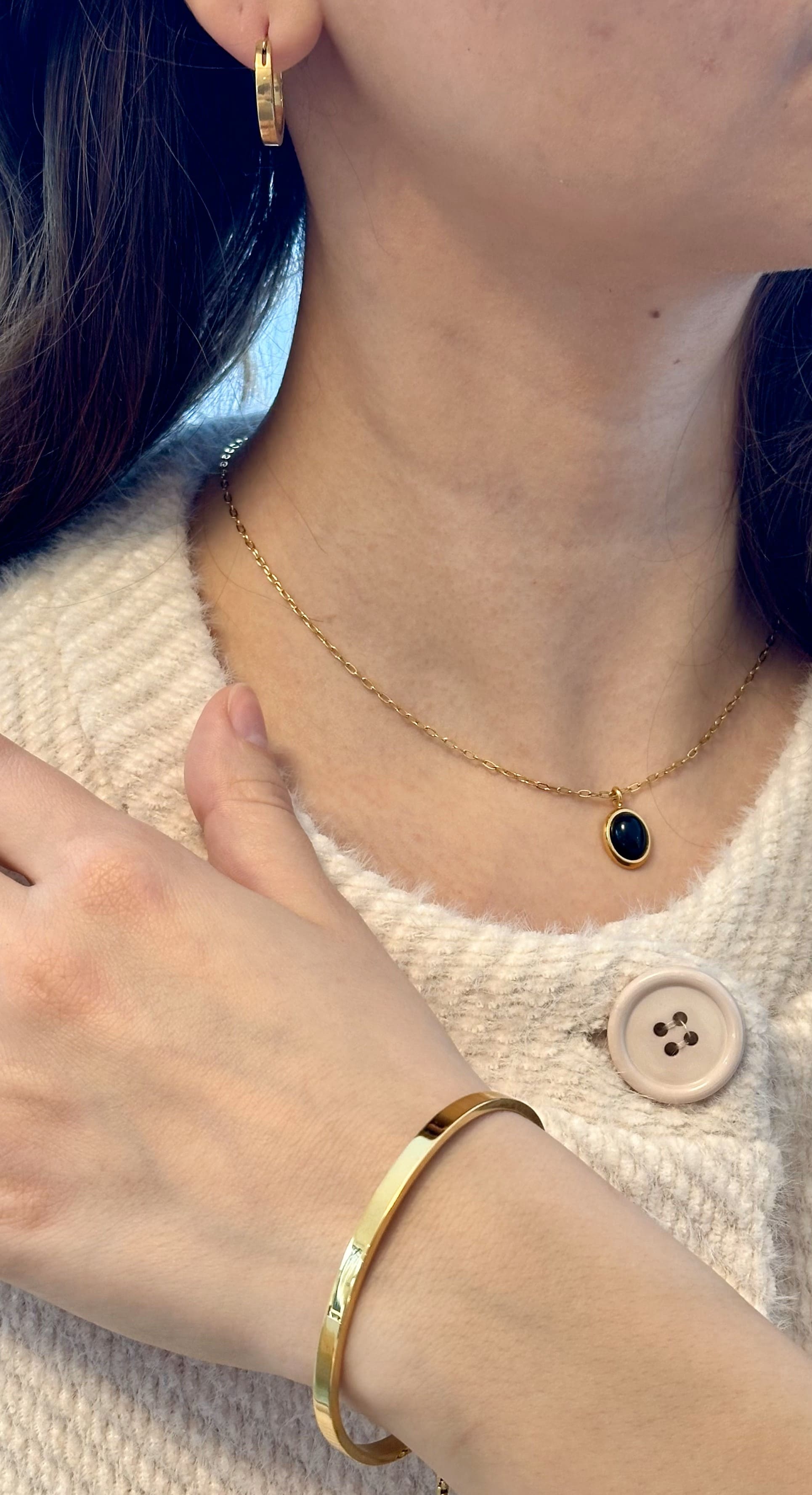 goldene, zierliche Halskette mit ovalem Anhänger in Schwarz- auf dem Bild trägt ein Model die Halskette