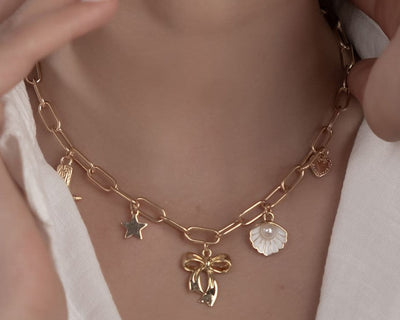 Goldene Charm-Halskette mit Schleife, Cowboy-Stiefel und Muschel, Modell Colette
