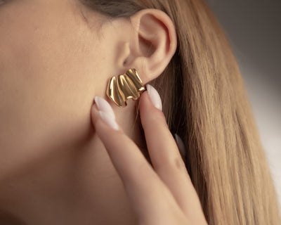 Abstrakte goldene Ohrstecker in organischer, gewellter Form